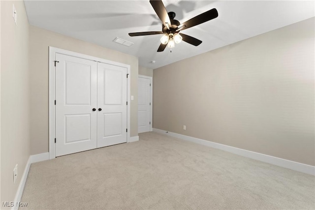 unfurnished bedroom with ceiling fan, a closet, and light carpet