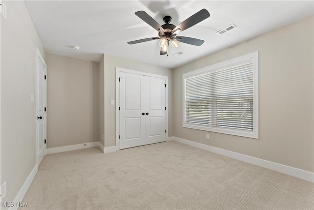 unfurnished bedroom featuring ceiling fan, a closet, and light carpet