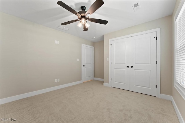 unfurnished bedroom featuring light carpet, a closet, and ceiling fan