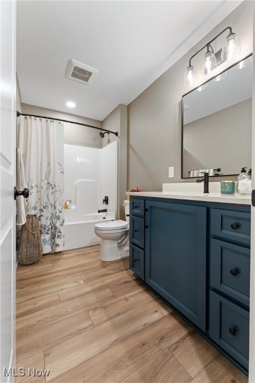 full bathroom featuring hardwood / wood-style floors, vanity, toilet, and shower / tub combo with curtain