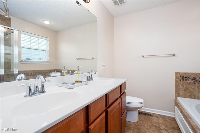 bathroom featuring a tub to relax in, vanity, a textured ceiling, and toilet