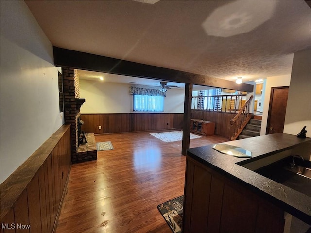 bar with hardwood / wood-style floors, wood walls, sink, ceiling fan, and a textured ceiling