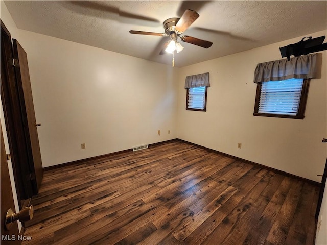 empty room with ceiling fan, dark hardwood / wood-style flooring, and a textured ceiling