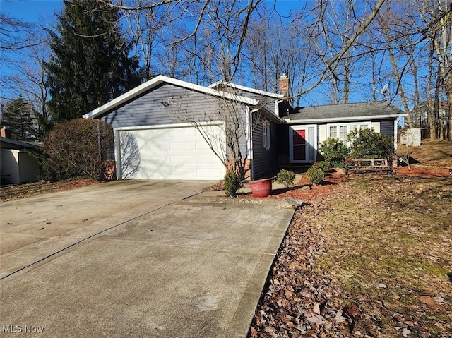 view of front of home featuring an attached garage, a chimney, and driveway