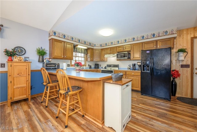 kitchen featuring a breakfast bar area, kitchen peninsula, stainless steel appliances, and light wood-type flooring