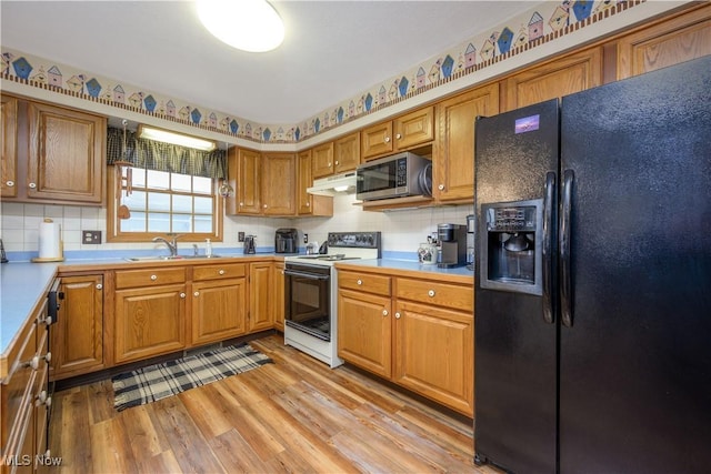 kitchen featuring sink, light hardwood / wood-style flooring, electric range, decorative backsplash, and black fridge with ice dispenser