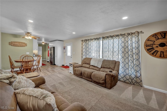 carpeted living room featuring ceiling fan and a textured ceiling