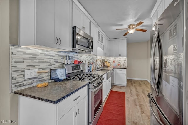 kitchen featuring appliances with stainless steel finishes, tasteful backsplash, ceiling fan, white cabinets, and light hardwood / wood-style floors