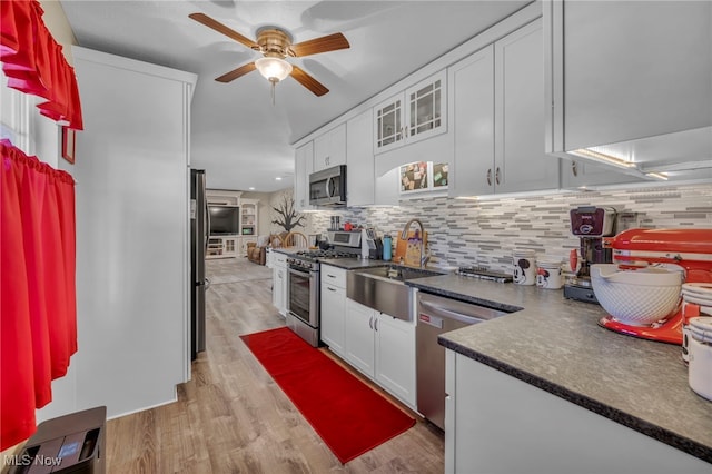 kitchen featuring white cabinets, sink, light hardwood / wood-style flooring, decorative backsplash, and stainless steel appliances