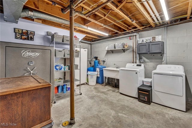 basement featuring washing machine and dryer, white fridge, and sink