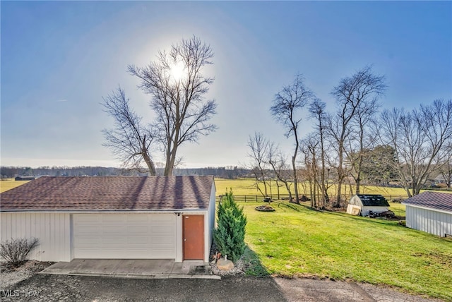 garage featuring a rural view and a lawn