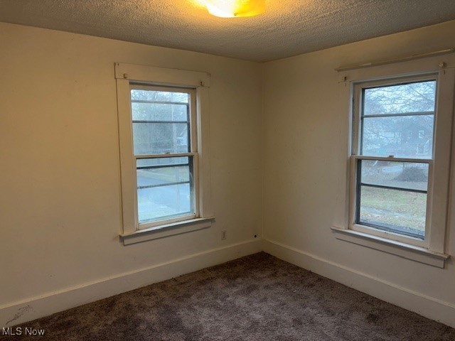 carpeted empty room featuring a textured ceiling