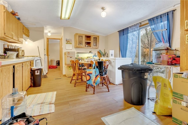 kitchen featuring white refrigerator, light wood-type flooring, lofted ceiling, and a textured ceiling