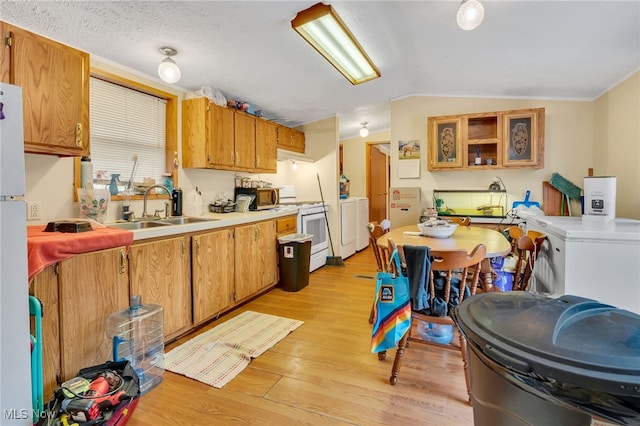 kitchen with sink, white range oven, lofted ceiling, washer / dryer, and light wood-type flooring