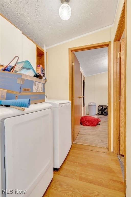 washroom with washer and clothes dryer, light wood-type flooring, a textured ceiling, and ornamental molding