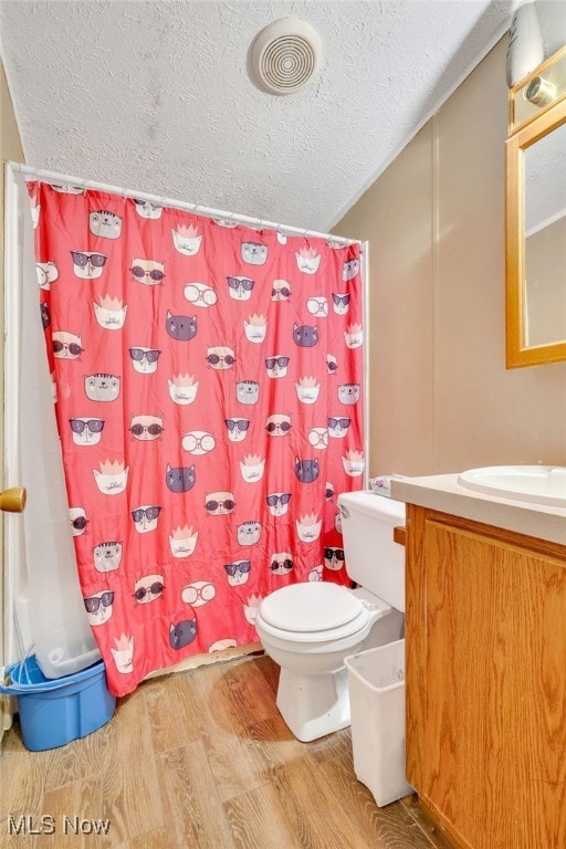 bathroom with a shower with curtain, vanity, a textured ceiling, hardwood / wood-style floors, and toilet