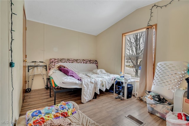 bedroom with vaulted ceiling and light hardwood / wood-style flooring