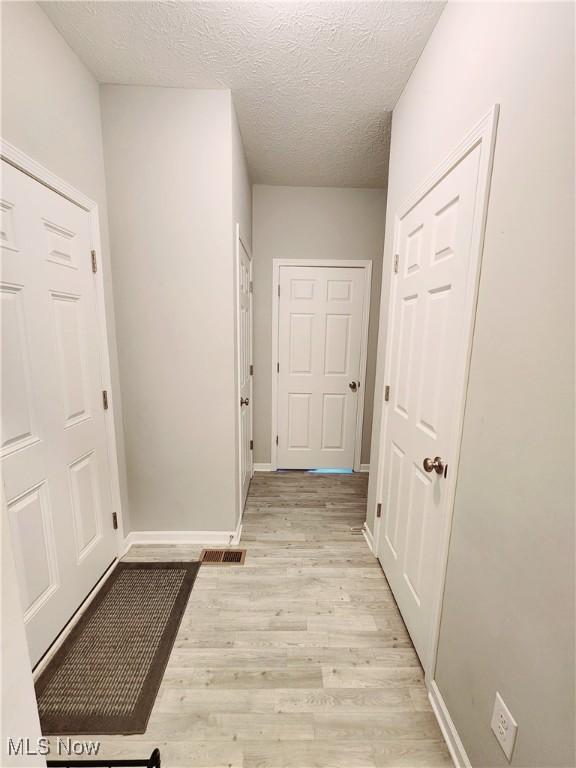 hallway featuring a textured ceiling and light hardwood / wood-style floors