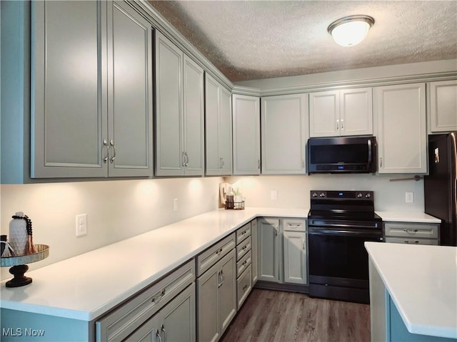 kitchen featuring dark hardwood / wood-style flooring, kitchen peninsula, a textured ceiling, and black appliances