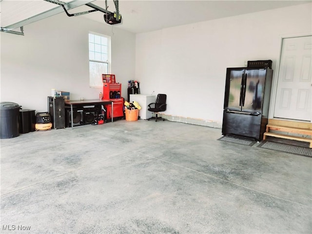 garage with a garage door opener and black fridge