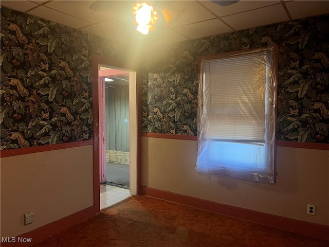 carpeted empty room featuring a drop ceiling