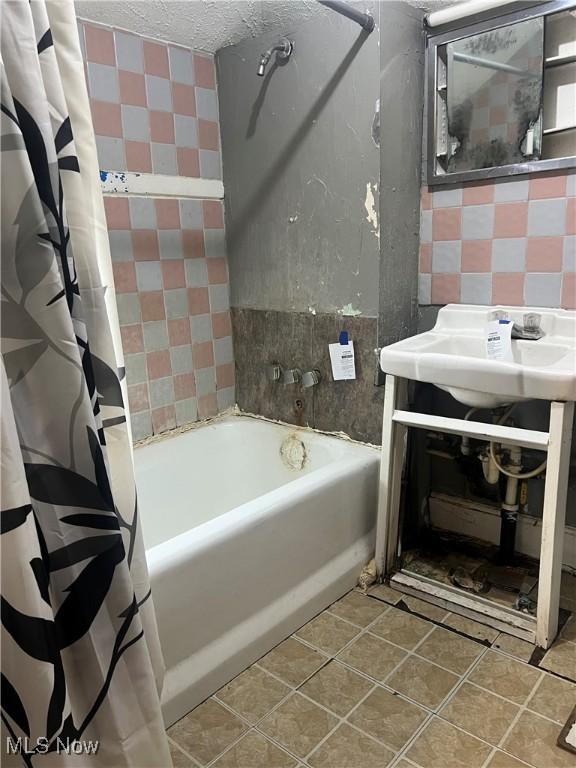 bathroom featuring a textured ceiling, shower / bath combo, and sink