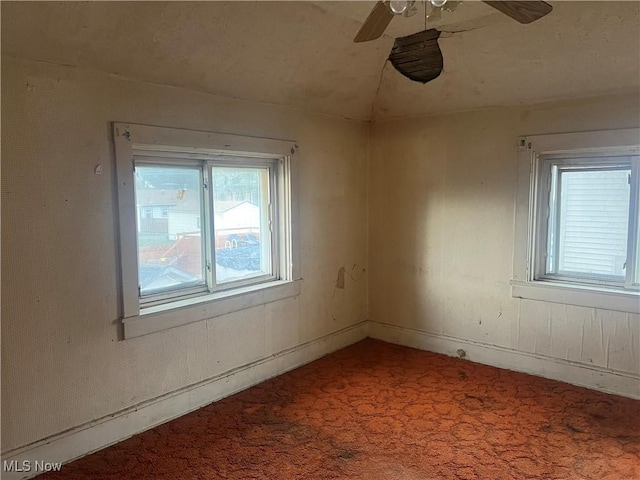 carpeted spare room with ceiling fan, plenty of natural light, and vaulted ceiling