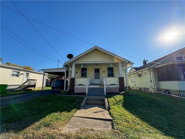 bungalow-style home with a carport, a porch, and a front yard