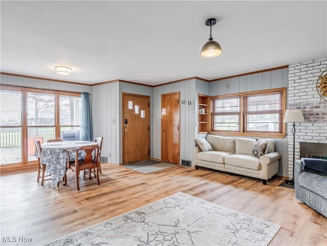 living room with light wood-type flooring, crown molding, and wood walls