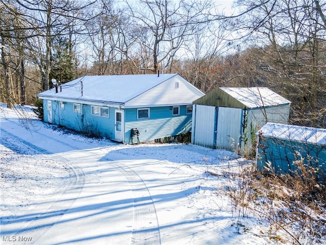 snow covered rear of property with an outdoor structure