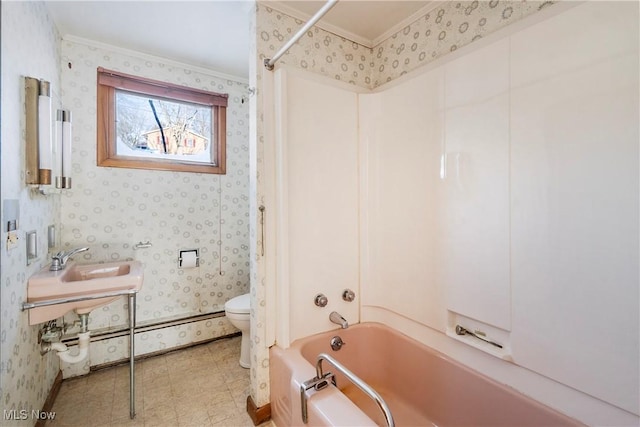 full bathroom with sink, washtub / shower combination, a baseboard heating unit, toilet, and ornamental molding