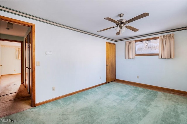 carpeted spare room with ceiling fan and ornamental molding