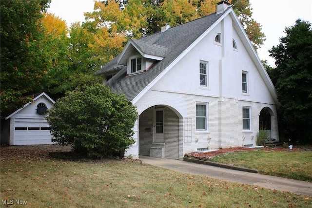 view of front of house with a garage, an outbuilding, and a front lawn