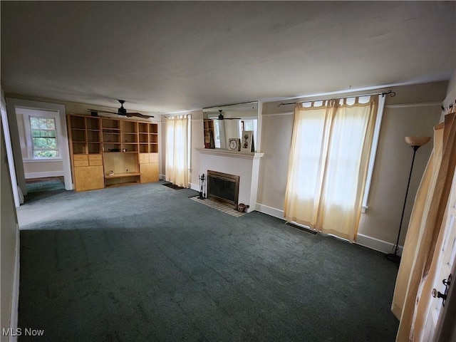 unfurnished living room with ceiling fan and dark colored carpet