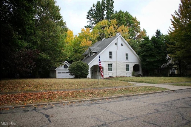 view of front of home featuring a garage, a front lawn, and an outdoor structure