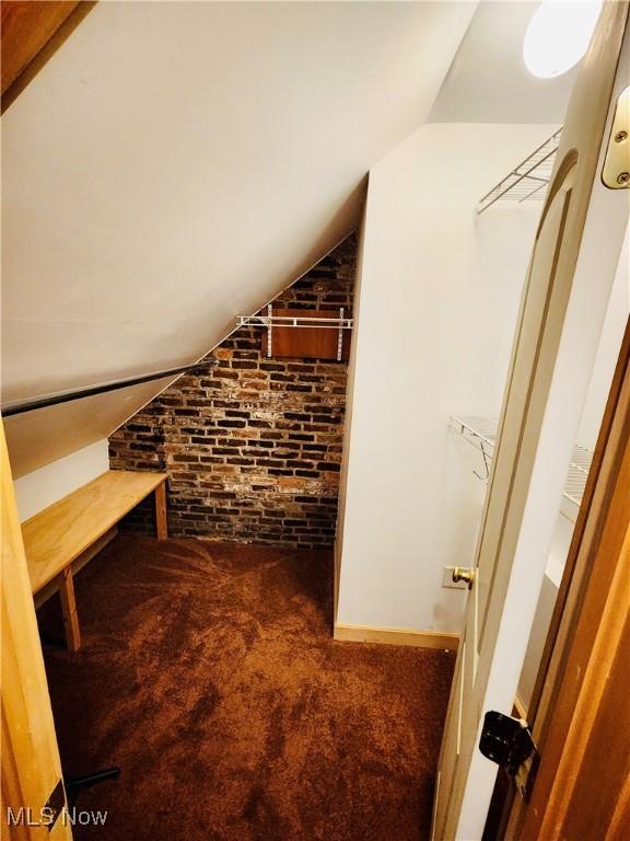 interior space featuring lofted ceiling and dark colored carpet