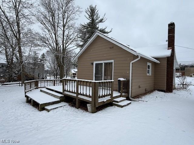 snow covered rear of property with a wooden deck