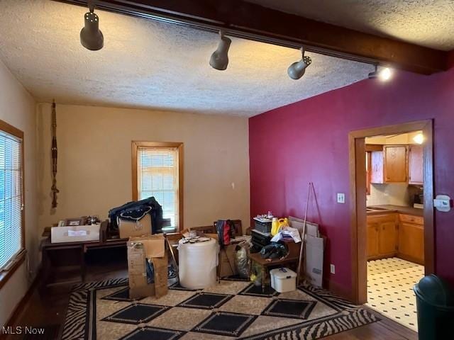 miscellaneous room featuring a textured ceiling, beam ceiling, a healthy amount of sunlight, and rail lighting