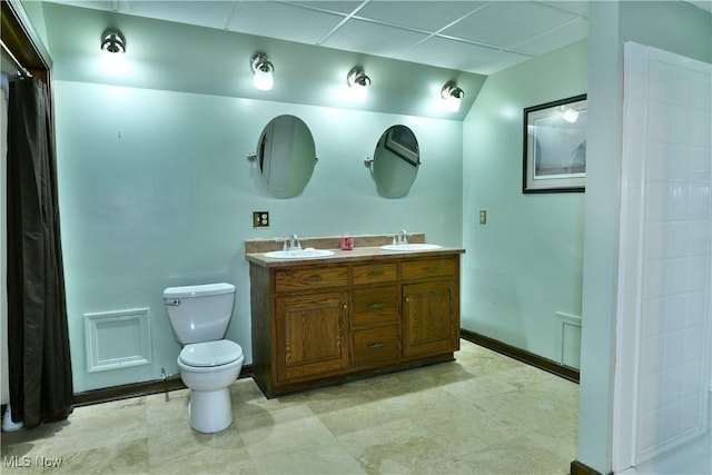 bathroom featuring vanity, toilet, and a drop ceiling