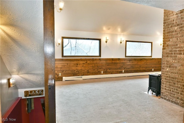 interior space featuring a textured ceiling, a wood stove, carpet floors, and wooden walls