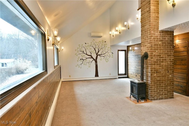 carpeted cinema room with a wall unit AC, a wood stove, a healthy amount of sunlight, and a baseboard heating unit