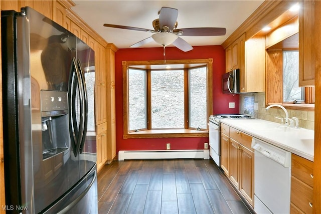 kitchen featuring decorative backsplash, baseboard heating, stainless steel appliances, and a wealth of natural light