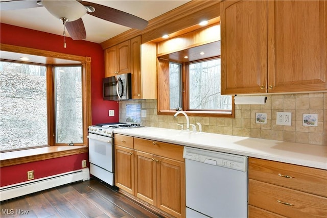 kitchen featuring ceiling fan, baseboard heating, dark hardwood / wood-style floors, white appliances, and decorative backsplash