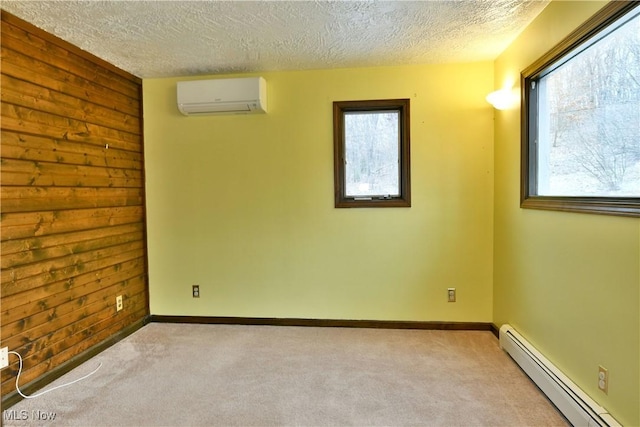 carpeted spare room featuring a wall mounted air conditioner, a textured ceiling, baseboard heating, and a healthy amount of sunlight