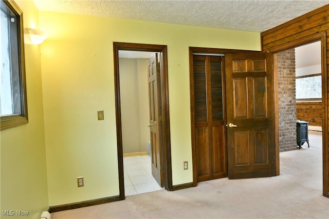 hallway with light colored carpet and a textured ceiling