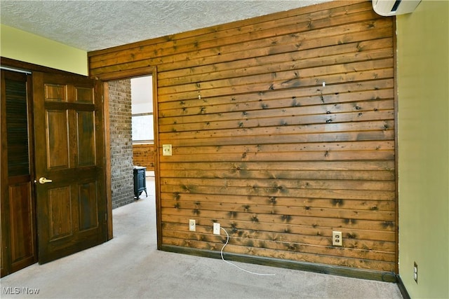 carpeted empty room with a textured ceiling and wood walls