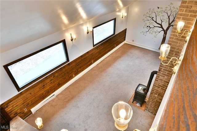 interior space featuring carpet, vaulted ceiling, a wealth of natural light, and wood walls