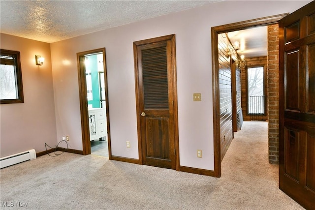 hallway with a textured ceiling, light colored carpet, and a baseboard heating unit