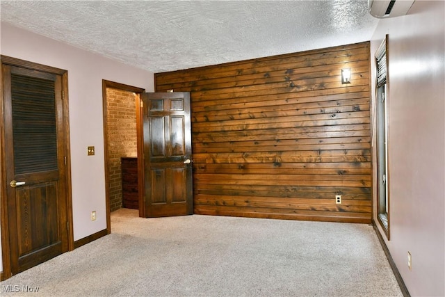 unfurnished bedroom featuring wooden walls, light carpet, and a textured ceiling