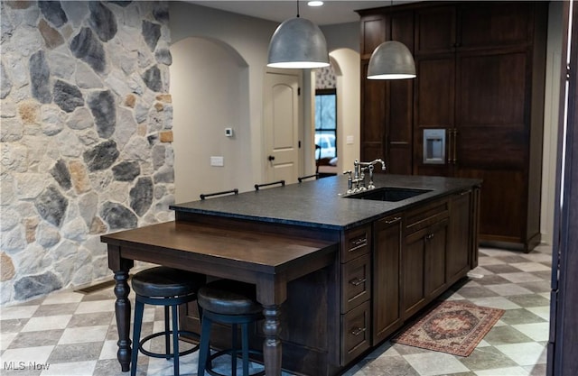 kitchen featuring sink, dark brown cabinets, and a center island with sink